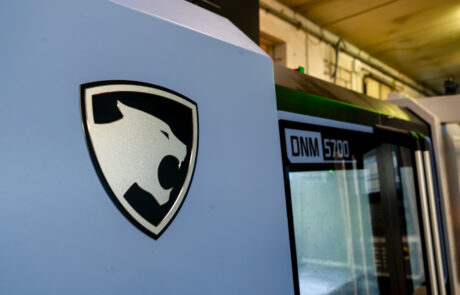 Zbliżenie na maszynę z logo pantery i napisem „DNM 5700” na boku, umieszczoną w otoczeniu przemysłowym.